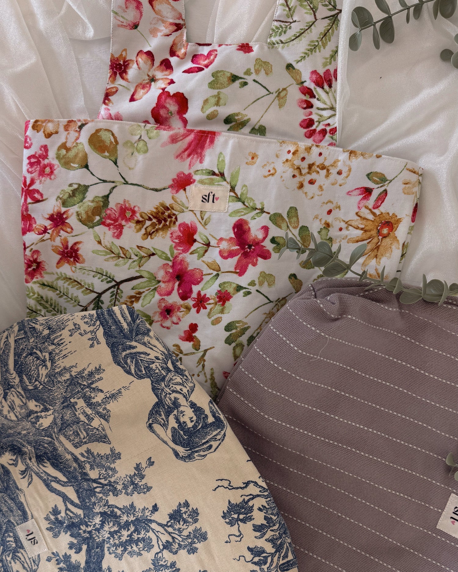 Three fabric bags with floral, toile, and striped patterns on a white background.