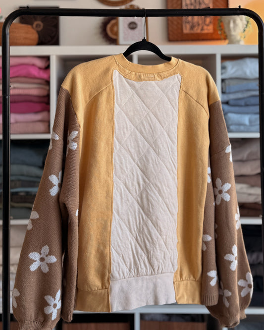 The back of a yellow patchwork sweater with a floral on brown and white quilted fabric